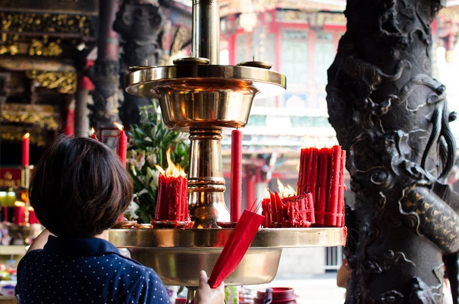 Woman lighting red candles in a Taiwanese temple, symbolizing prayer and offerings.