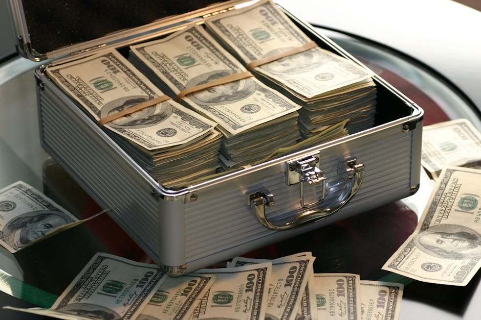 Open briefcase filled with stacks of hundred dollar bills on a glass table, representing wealth.feng shui